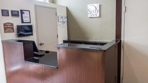 Un comptoir d’accueil avec une enseigne « Sleep Inn », une porte et plusieurs affiches encadrées accrochées au mur.