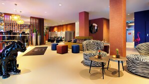 A modern lobby with a zebra-striped sofa, a black dog statue, and a bar area. - NYX Hotel Mannheim by Leonardo Hotels (Mannheim)