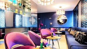 A modern lounge area with purple chairs, a sofa, and a round table with a cactus. - NYX Hotel Mannheim by Leonardo Hotels (Mannheim)