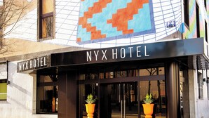 The NYX HOTEL entrance with a large sign, two potted plants, and a colorful mosaic above the entrance. - NYX Hotel Mannheim by Leonardo Hotels (Mannheim)