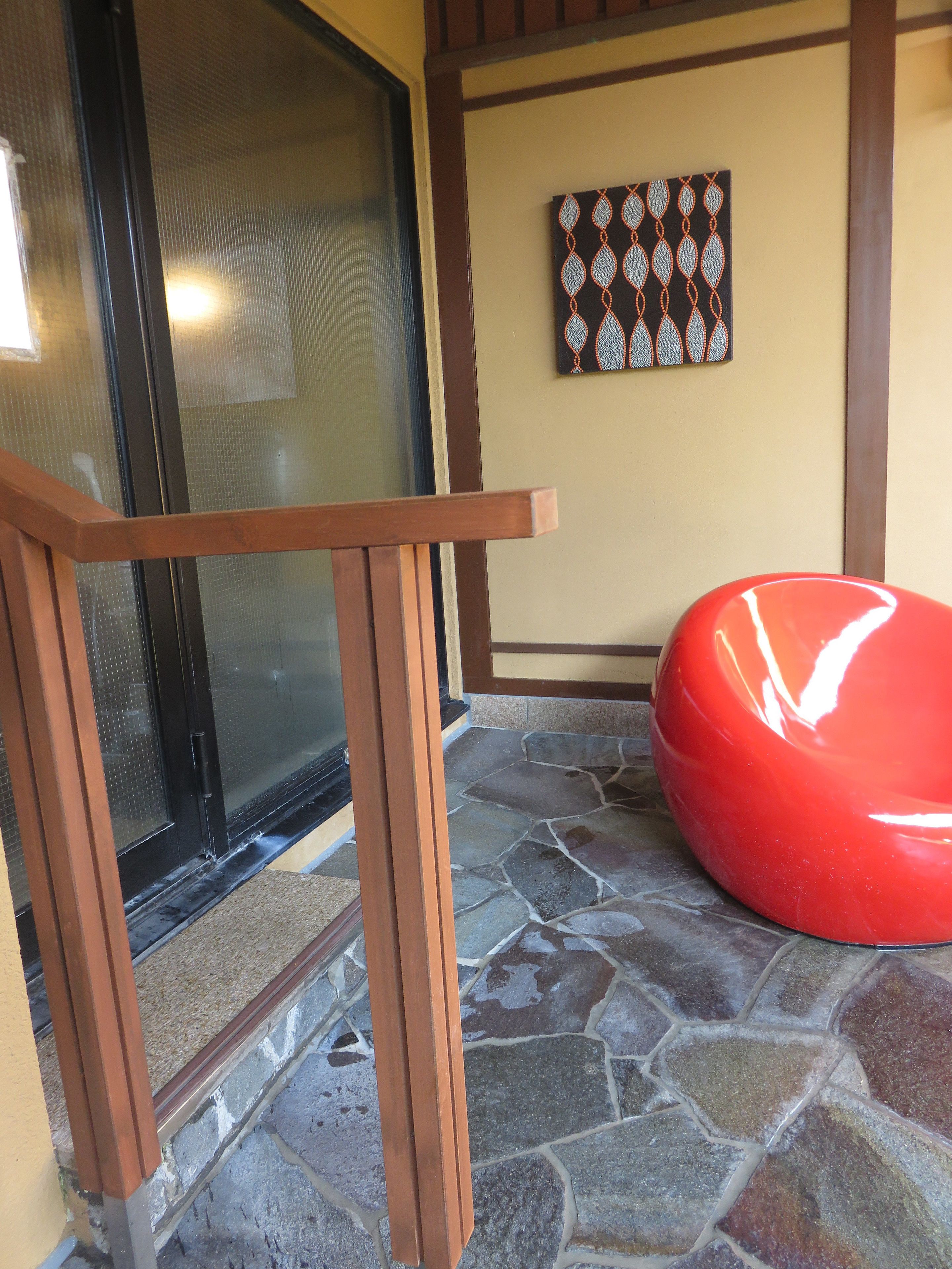 A stone-tiled entrance with a wooden bench and a door with a glass panel.