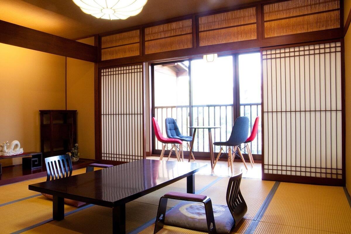 A traditional Japanese room with tatami flooring, a low table, and sliding doors.