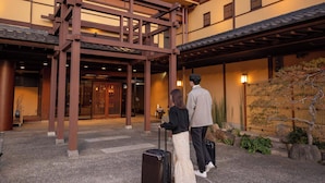 A traditional Japanese building entrance with a wooden structure, a stone pathway, and a small garden area. - Dantoukan Kikunoya (Otsu)