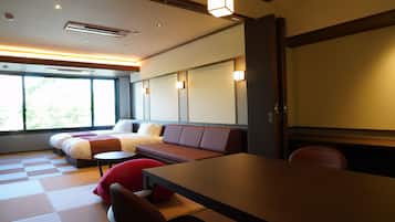 Habitación de hotel moderna con una cama grande, un sofá, una mesa de comedor y vistas a zonas verdes.