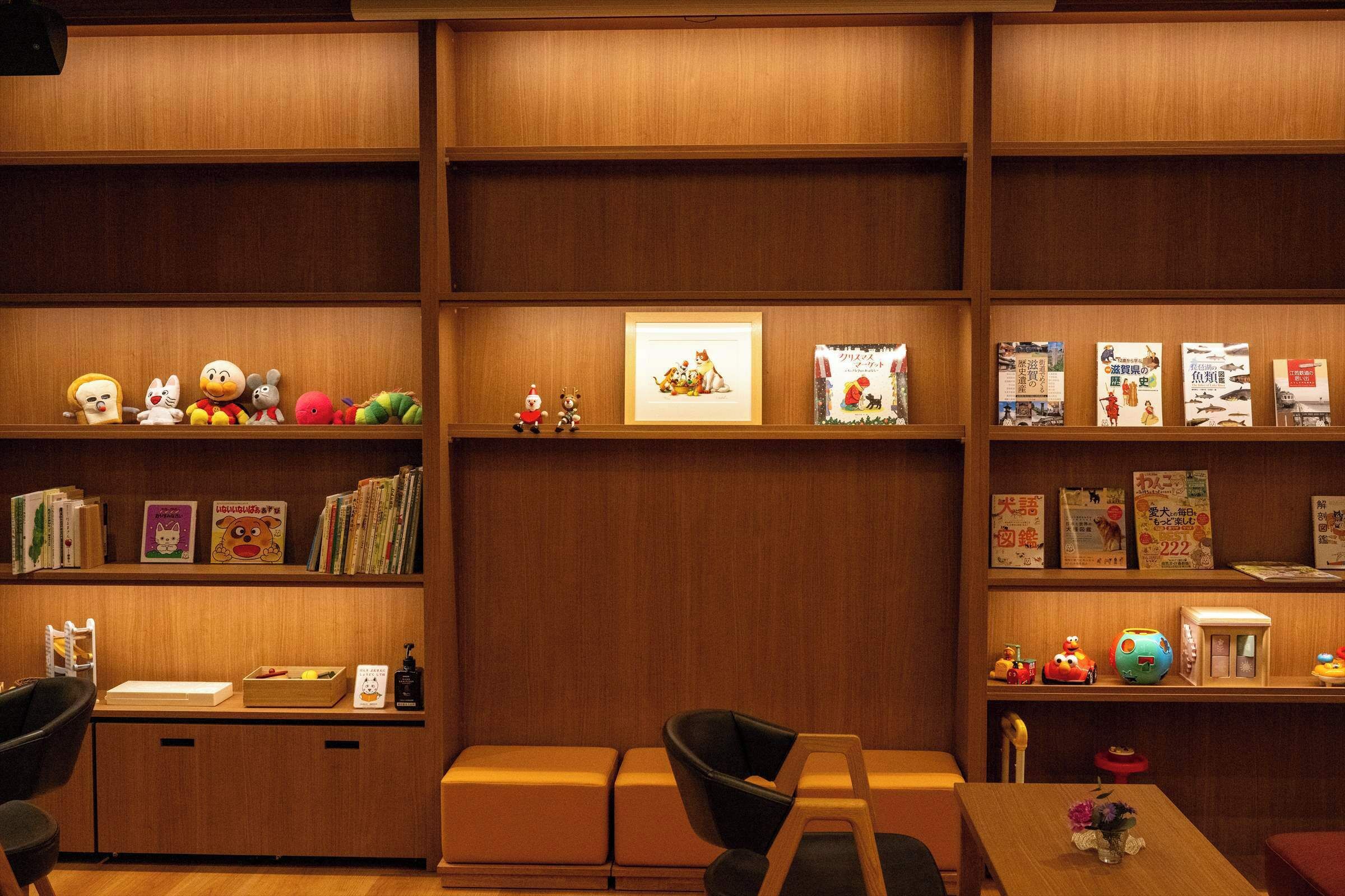 A cozy library with wooden shelves, books, and plush toys.