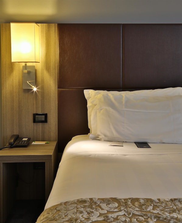A hotel room with a bed, a bedside table with a phone, a lamp, and a wall-mounted control panel. - Best Western Plus BorgoLecco Hotel (Arcore)