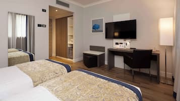 Habitación de hotel con dos camas, un escritorio, un televisor y un pequeño rincón de descanso.