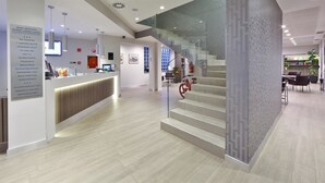 Un moderno vestíbulo de hotel con una recepción, una escalera y un comedor.