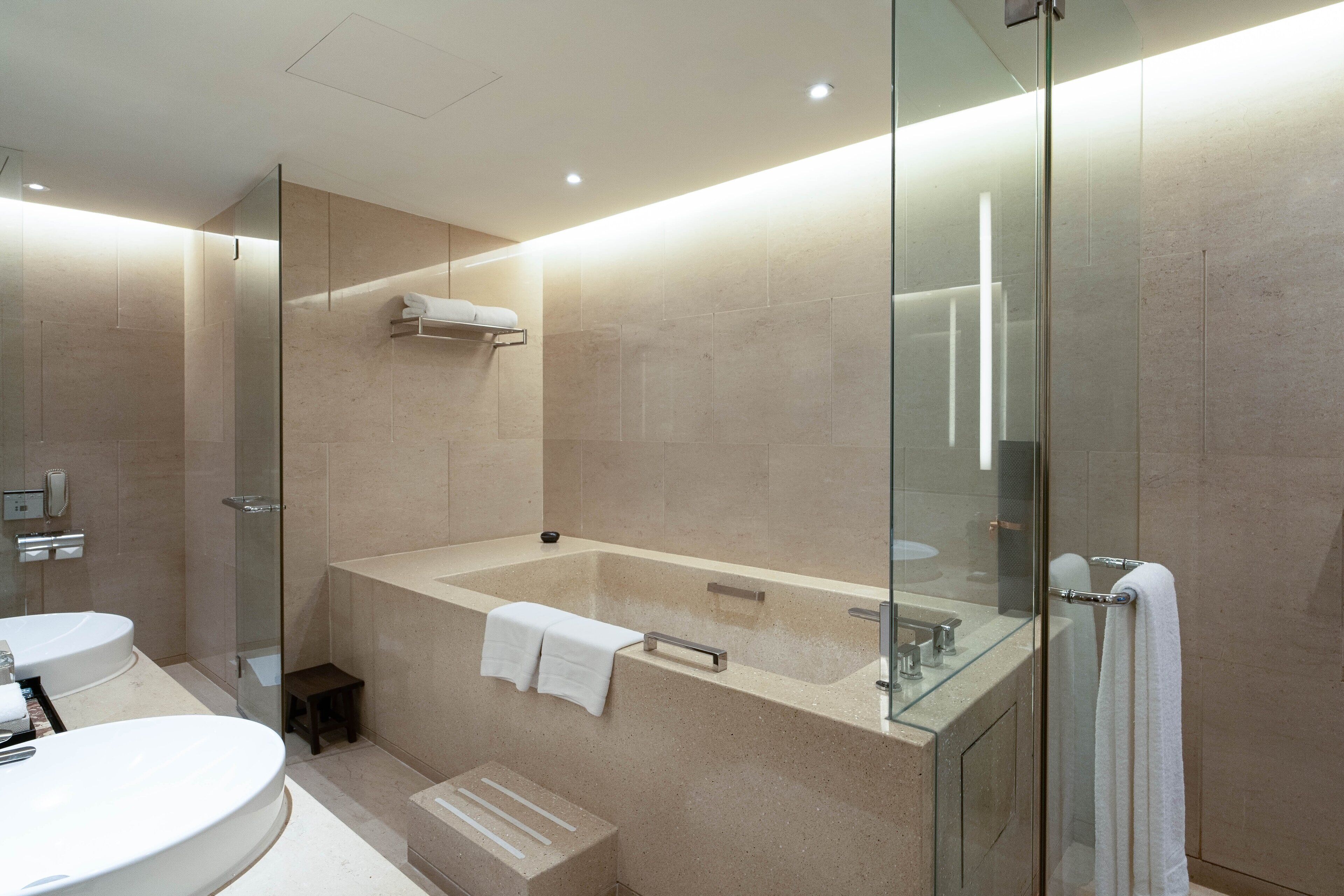 Een moderne badkamer met een douchecabine van glas, een vrijstaand bad en een wastafelmeubel.