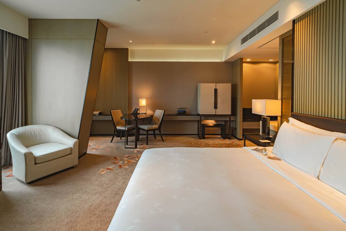 Una habitación de hotel con una cama grande, un escritorio con una silla, un refrigerador y una nevera.