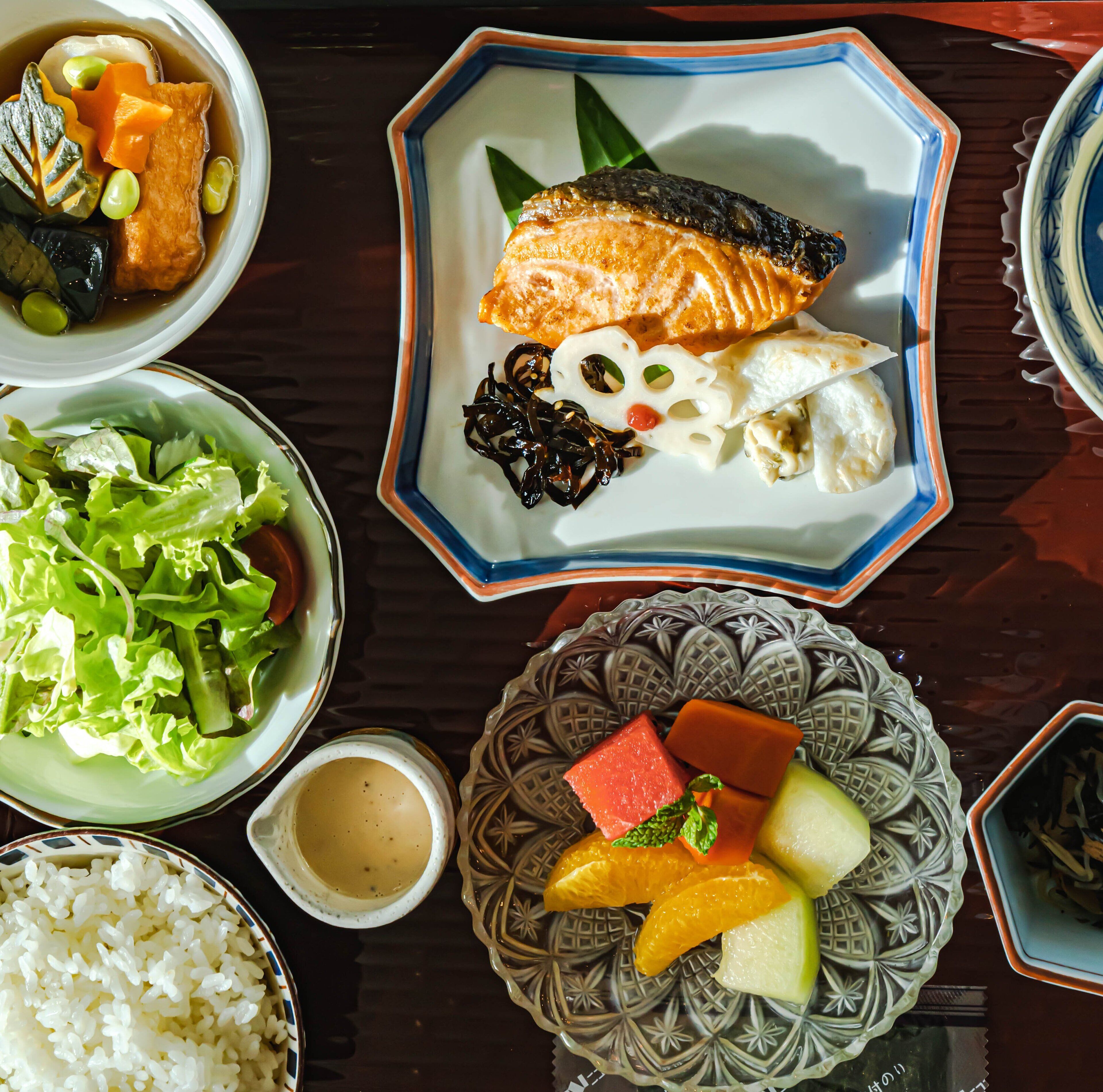 Variedad de platos que incluyen salmón, arroz y diversos vegetales sobre una mesa.