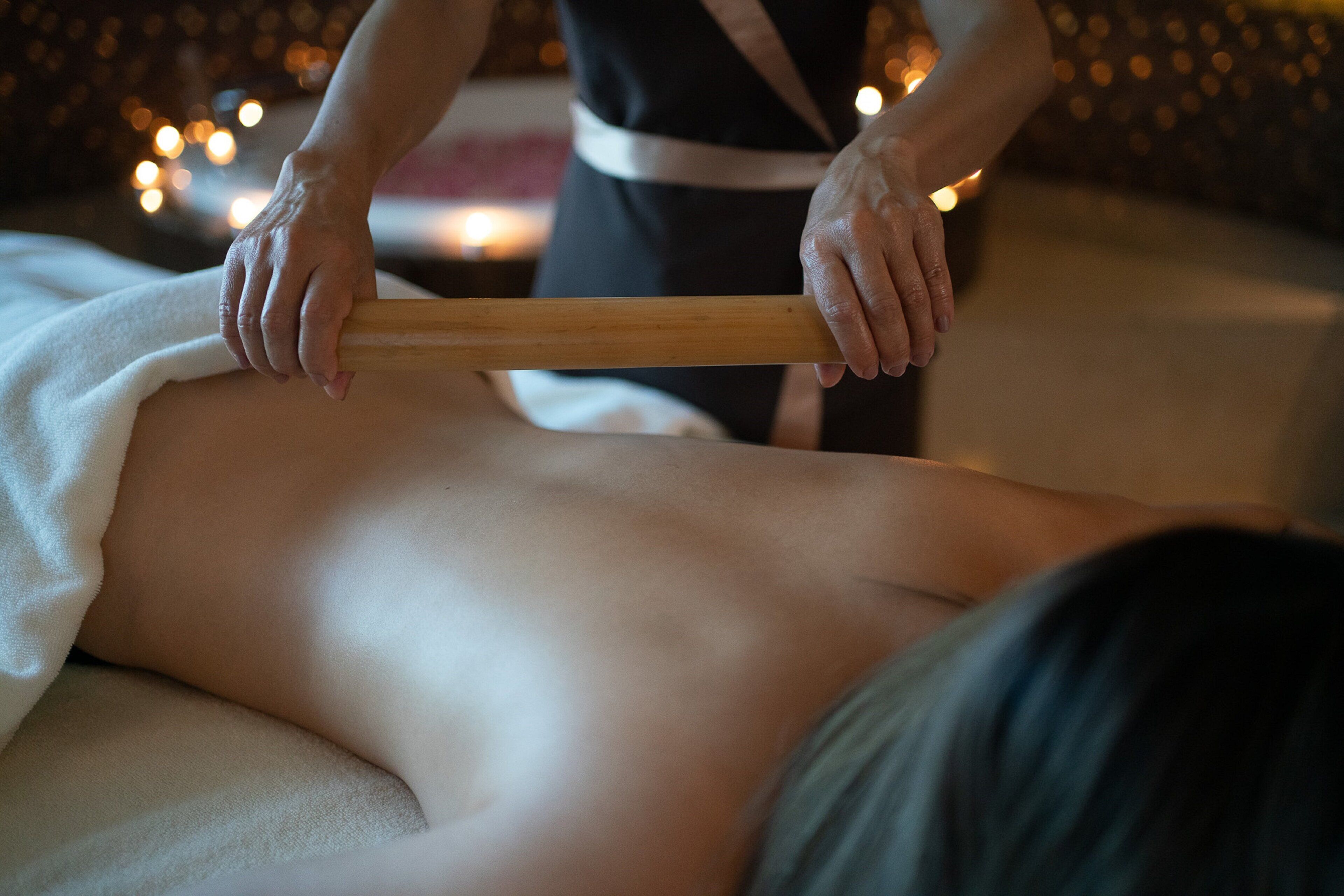A massage therapy session with a wooden tool being used on a client's back.