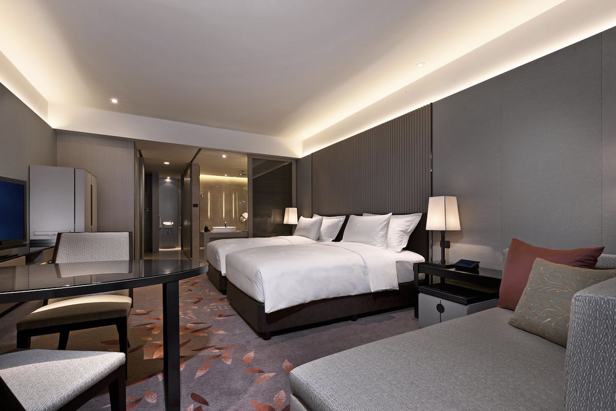 Una habitación de hotel moderna con una cama grande, un escritorio y una zona de estar.