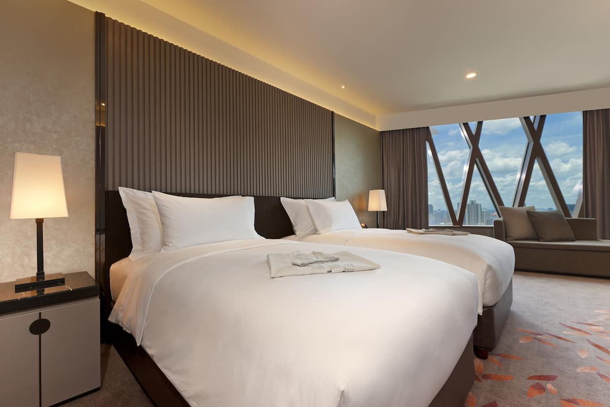 Habitación de hotel con dos camas, un sofá y vistas a la ciudad.