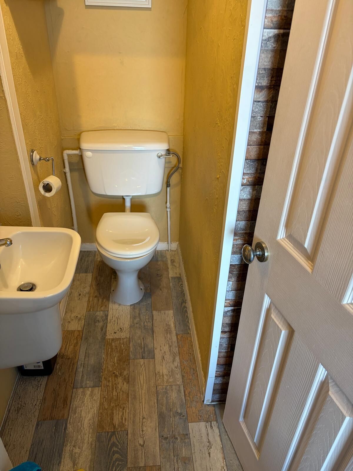 A bathroom with a toilet, bidet, and wooden flooring.