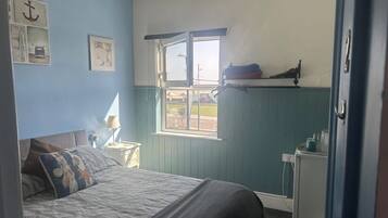 A bedroom with a bed, a window, a nightstand, and a dresser.