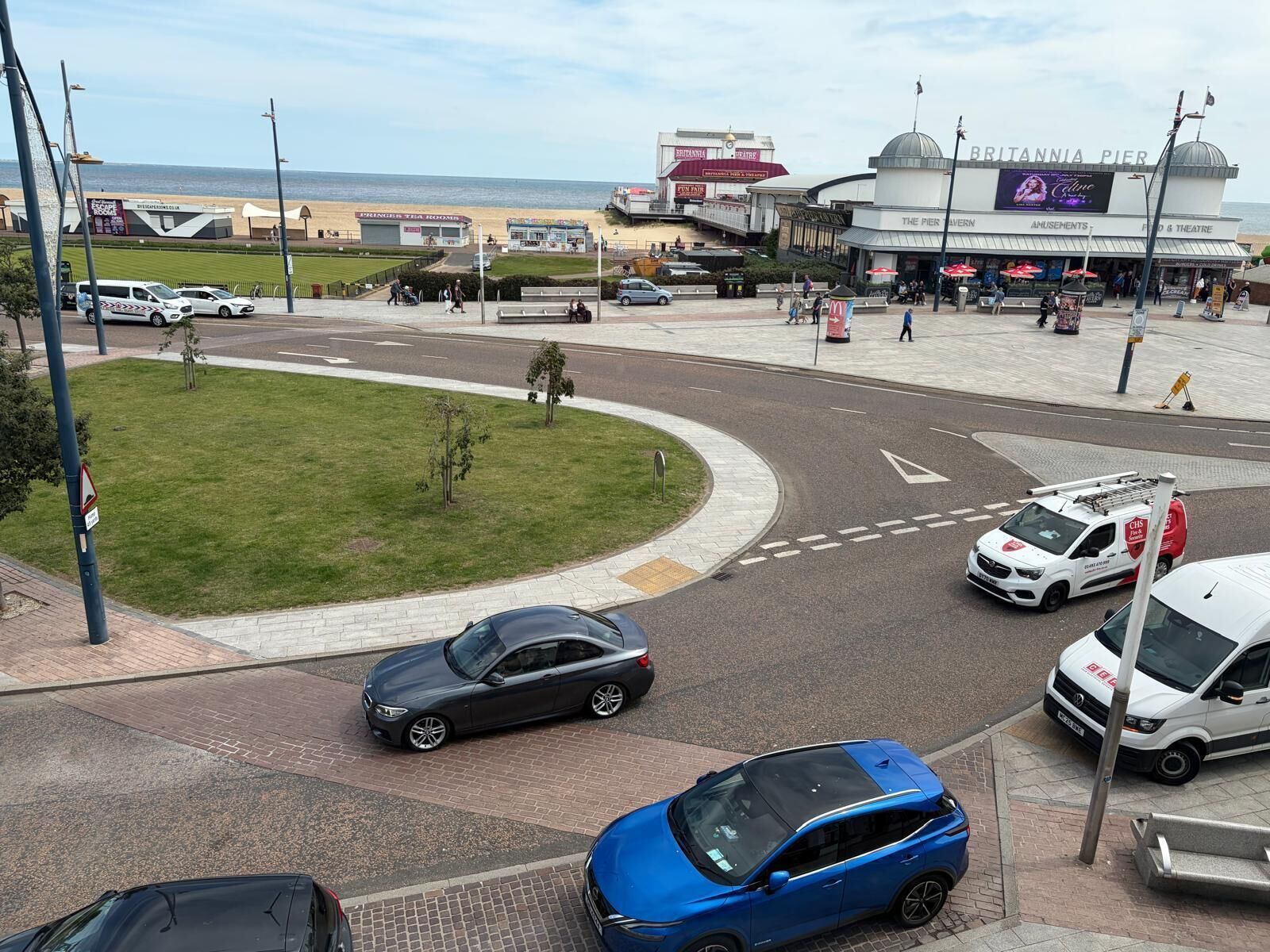 A roundabout with cars, a grassy area, and a building with 'BRITANNIA PIER' signage.