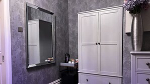 A bathroom with a large mirror, a white cabinet, and a trash bin. - Delovely Hotel (Blackpool)