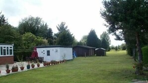 A residential property with a small house, a patio with outdoor furniture, and a well-maintained lawn. - London Heathrow Guesthouse (Slough)