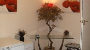 A room with a glass table, a potted plant, and two wall-mounted paintings. - London Heathrow Guesthouse (Slough)