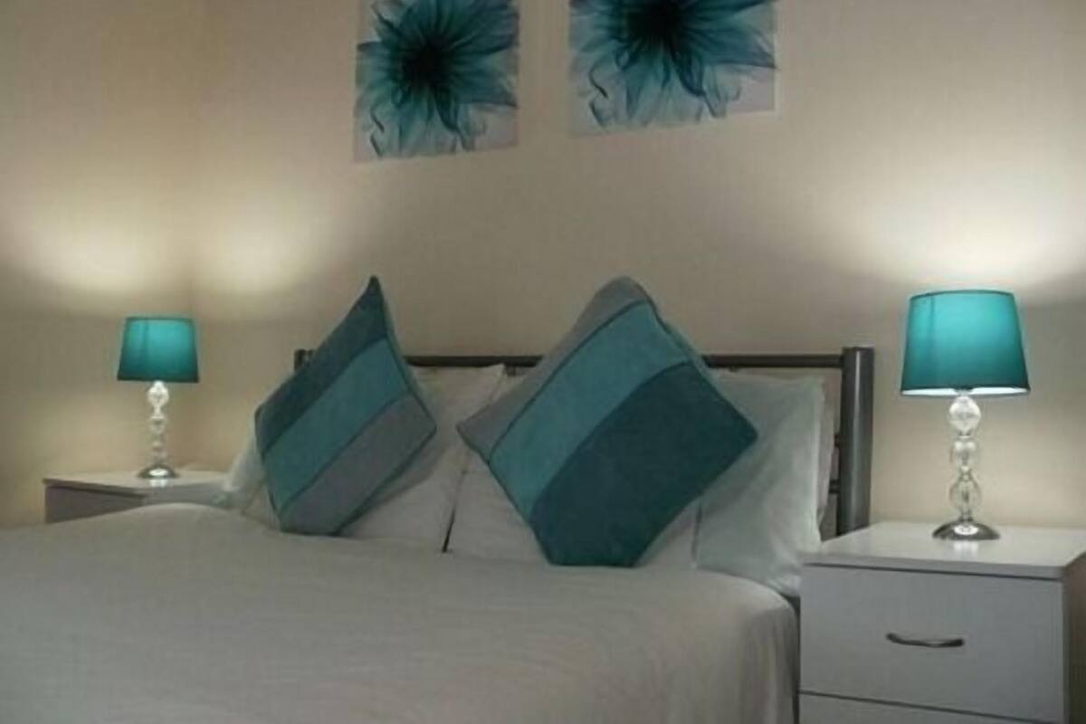 A bed with two pillows, a nightstand, and a lamp on each side.