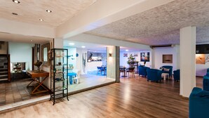Amplia sala de estar con piso de madera, un separador de vidrio y muebles azules.
