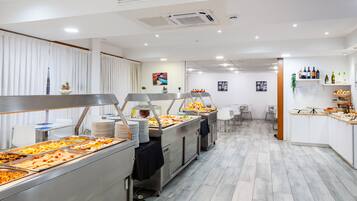 A buffet area with multiple food stations, white chairs, and a clean, modern design.