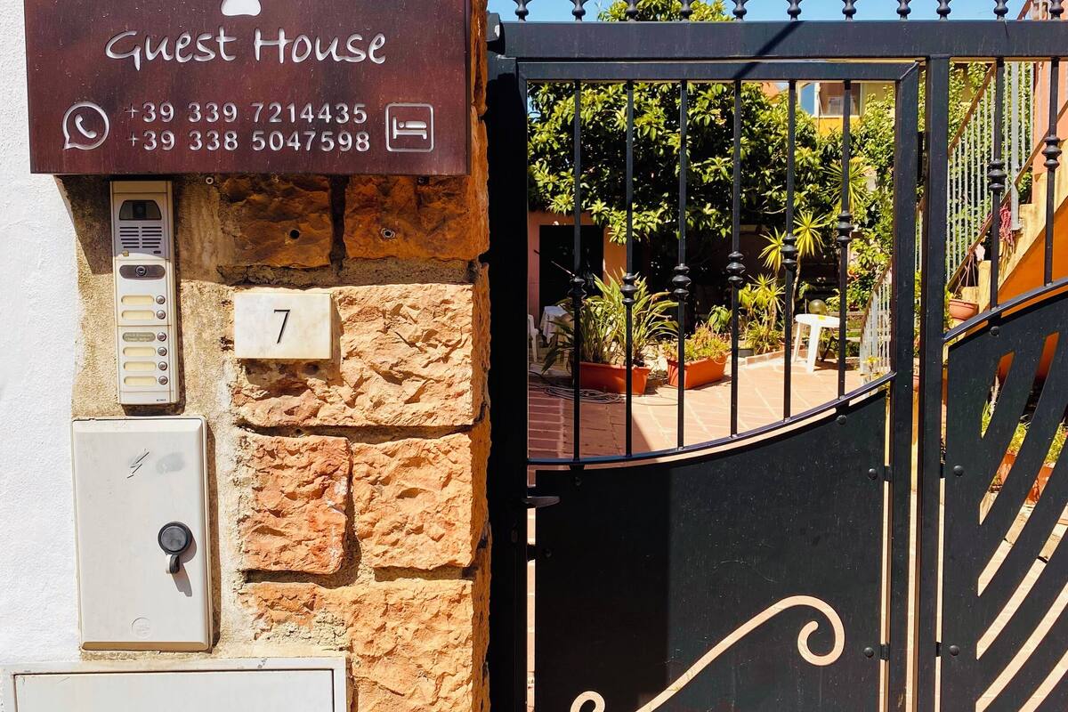 A guest house sign with contact numbers and a pet paw print symbol.