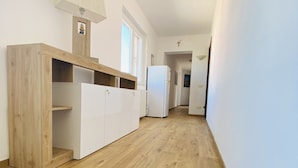 A narrow hallway with wooden flooring, white walls, and a white refrigerator. - Affittacamere Ciro's House (Olbia)