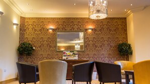 A lobby with patterned wallpaper, a chandelier, and several chairs. - Newcastle Jesmond Hotel (Newcastle-upon-Tyne)