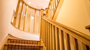 A wooden staircase with a curved design, a handrail, and a carpeted landing. - Newcastle Jesmond Hotel (Newcastle-upon-Tyne)