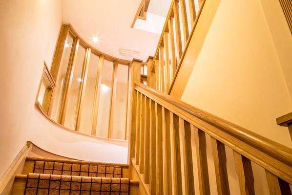 A wooden staircase with a curved design, a handrail, and a carpeted landing. - Newcastle Jesmond Hotel (Newcastle-upon-Tyne)