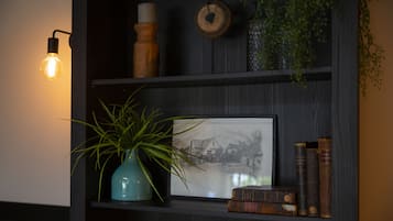 A dark wooden shelf with a framed black and white photograph, a blue vase with green plants, and several old books.