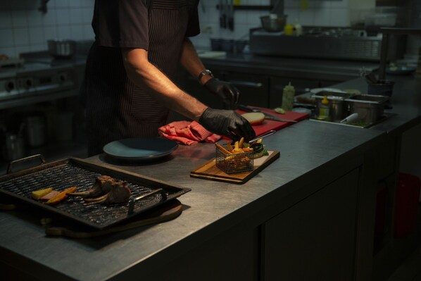 A chef preparing food in a kitchen with stainless steel countertops and various cooking utensils.