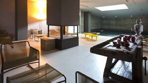 Een modern interieur met een zithoek, een centrale tafel met rode bekers en een groot raam dat voor natuurlijk licht zorgt.