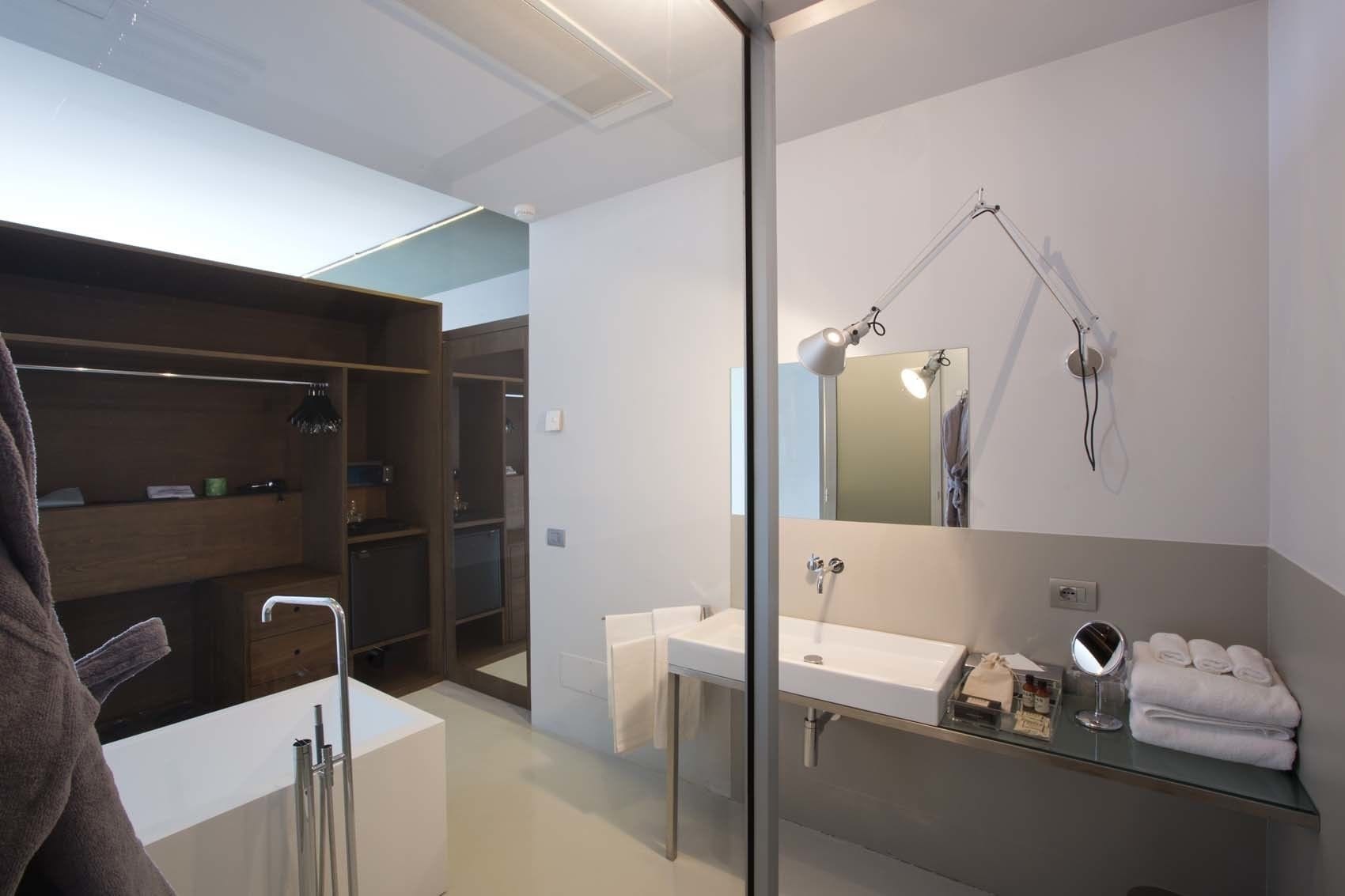 Un bagno moderno con box doccia in vetro, uno specchio grande e un mobile lavabo con lavandino e portasciugamani.