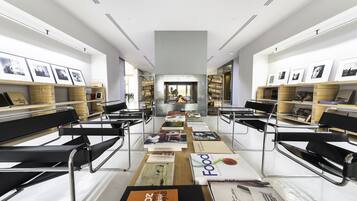 A modern library with bookshelves, reading tables, and black leather chairs.