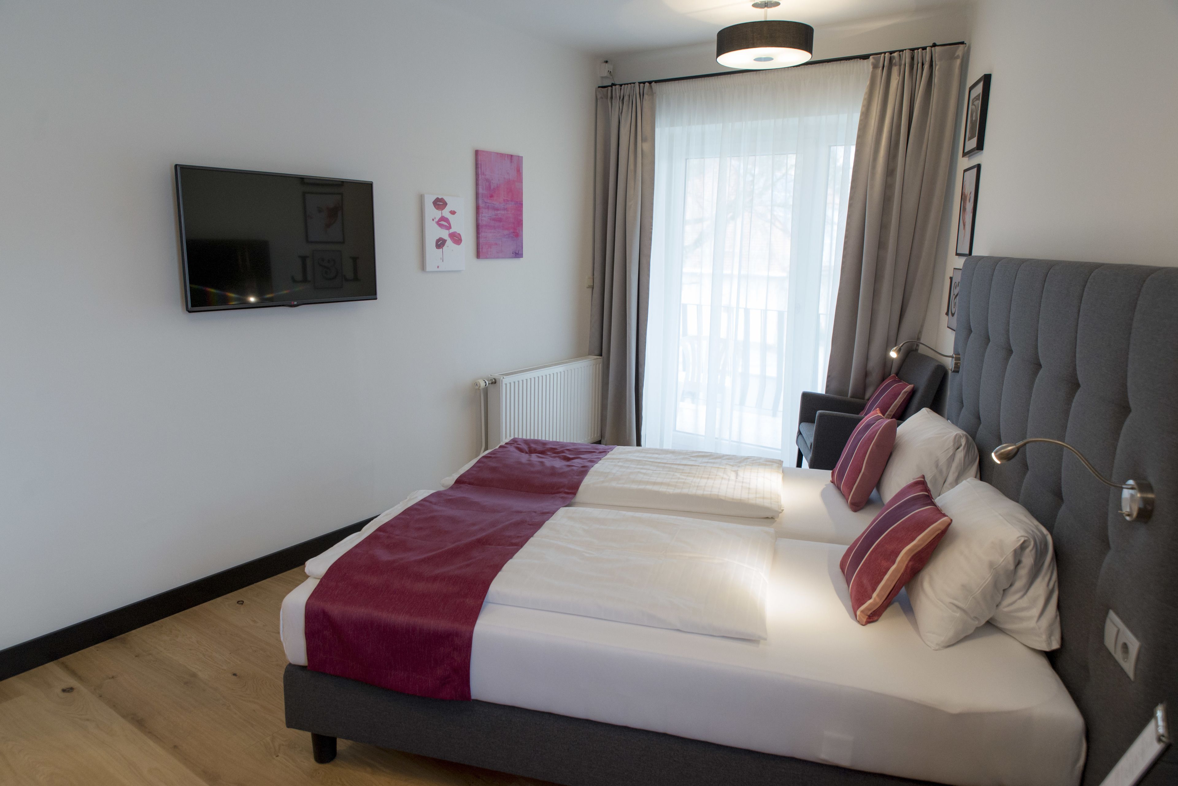 A modern bedroom with a large bed, a flat-screen TV, and a window with curtains.