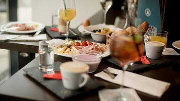 A dining table with various dishes, drinks, and a laptop.