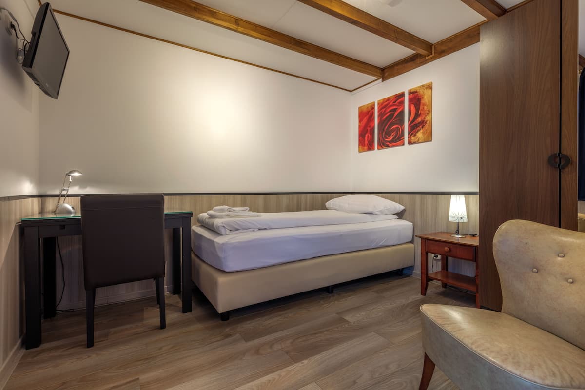 Ein Schlafzimmer mit Bett, Schreibtisch, Stuhl und Kunstwerk an der Wand.