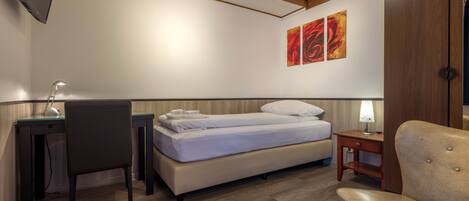 Un dormitorio con cama, escritorio, silla y una obra de arte en la pared.