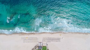Vue aérienne d’une plage avec une rangée de chaises longues rondes et un poste de surveillance pour les sauveteurs.