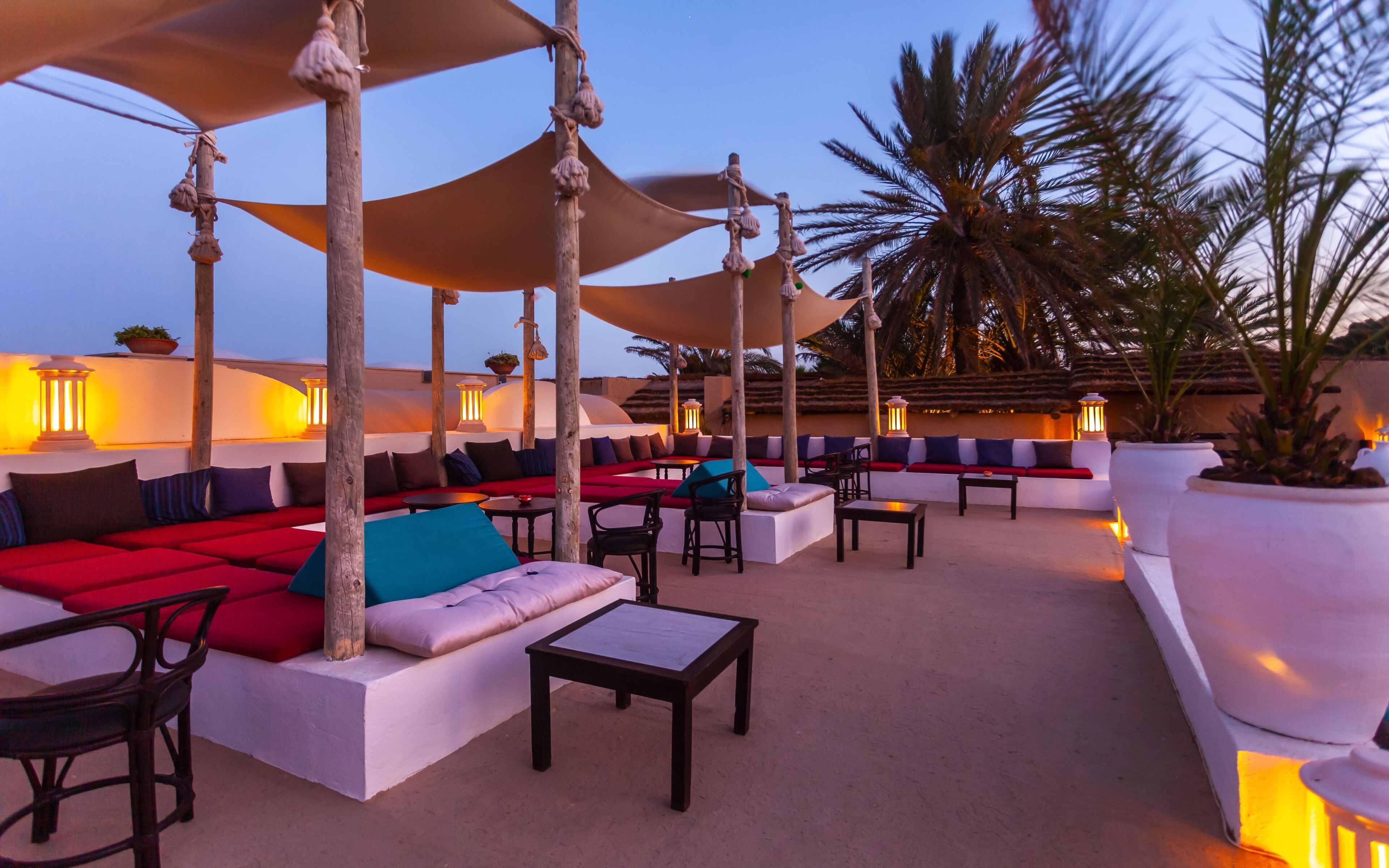 Een dakterras met buitenmeubels, waaronder banken en stoelen, onder grote parasols.
