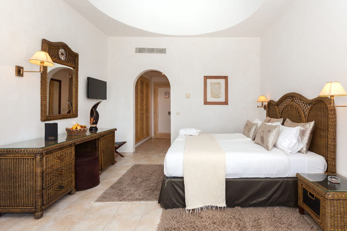 A bedroom with a large bed, a dresser, a television, and a mirror.