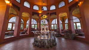 Un intérieur spacieux agrémenté de fenêtres en arc de cercle, d’un lustre central et de plusieurs coins salon.