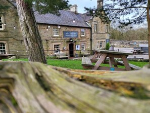 A stone building with a sign reading 'The Manifold Inn' and outdoor seating.