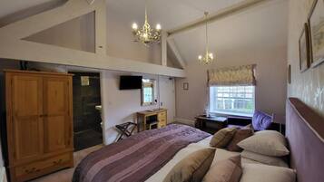 A bedroom with a large bed, wooden wardrobe, and a desk with a chair.