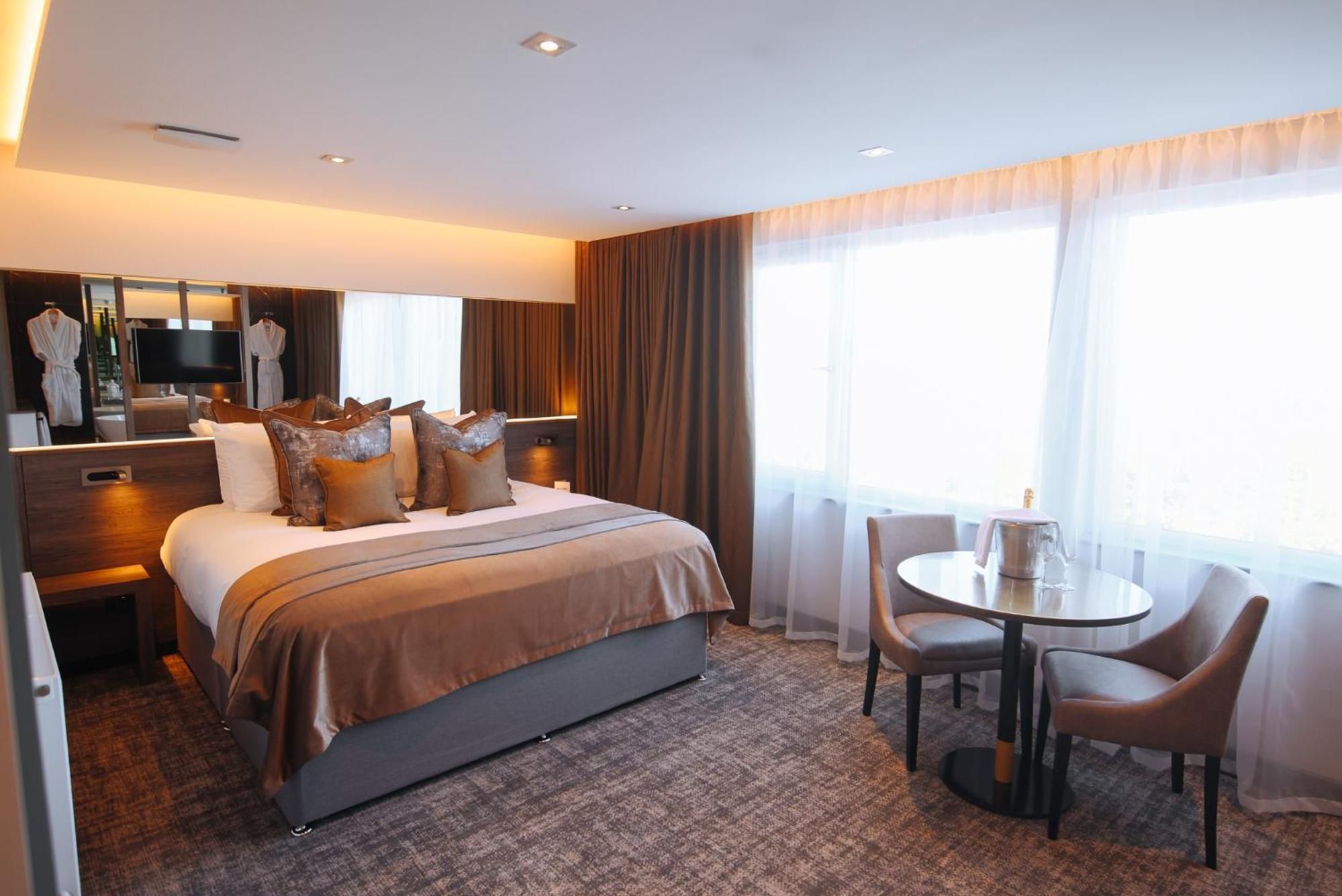 A hotel room with a bed, a desk, a chair, and a table.