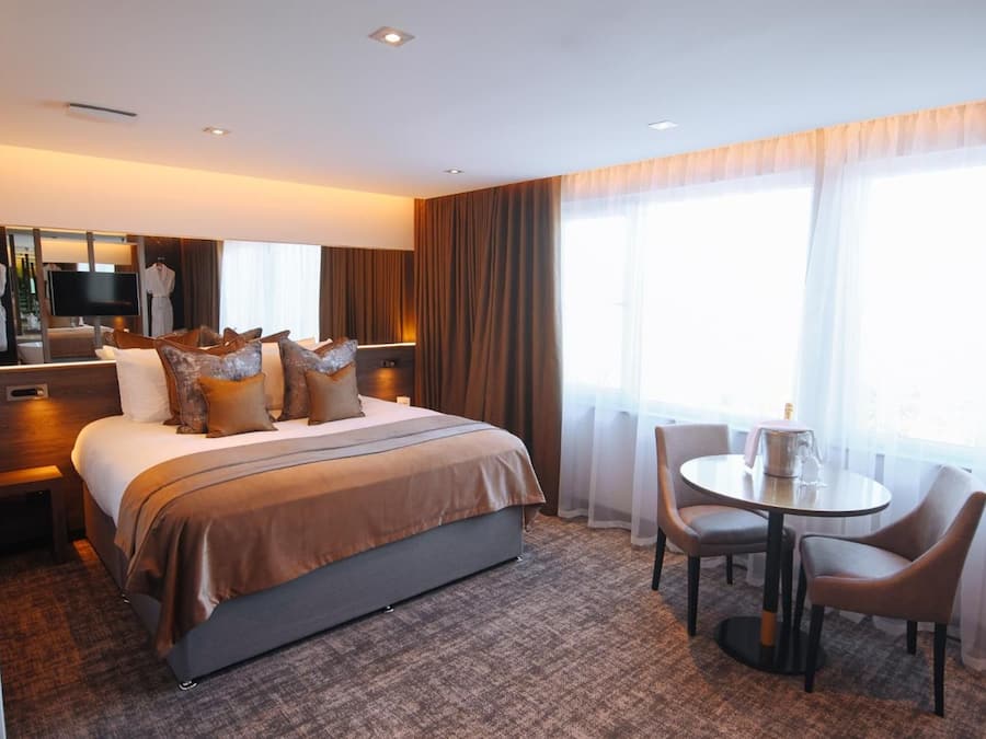 A hotel room with a bed, a desk, a chair, and a table.
