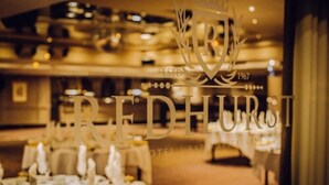 A restaurant interior with tables set for dining, a chandelier, and a sign indicating the establishment's name and year of establishment. - The Redhurst Hotel (Glasgow)